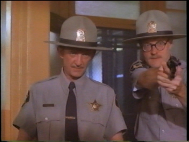 That's me, providing back-up for Police Chief Benny (Wayne Robson) in Paul Shapiro's Heads (1994): no, I didn't receive any training on how to hold a gun properly (frame grab from the long out-of-print VHS)