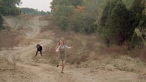 Sandra (Leslie Ann Rivers) runs from Eddie (Jack Canon), though by now he has become her protector in Frederick R. Friedel's Kidnapped Coed (1975)