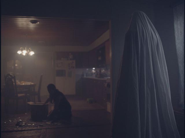 The ghost watches the house's new occupant clean up the mess he's made in David Lowery's A Ghost Story (2017)