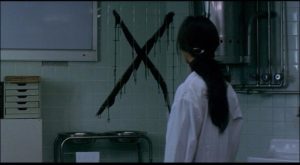 A doctor discovers the sign of the killer after examining Mamiya in Kiyoshi Kurosawa's Cure (1997)