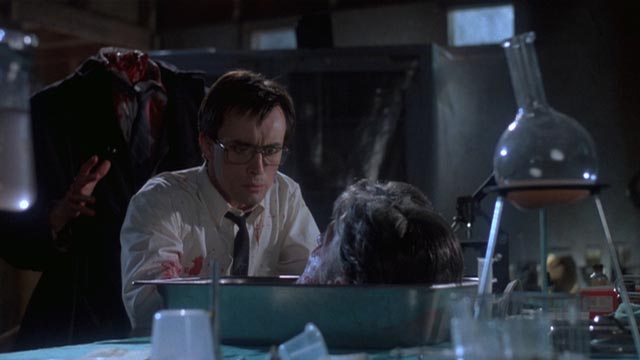 Herbert West (Jeffrey Combs) chats with the revived head of his academic nemesis in Stuart Gordon's Re-Animator (1985)