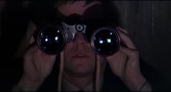 British agent Gatiss (Tom Courteney) spies on fellow spy Eberlin (Laurence Harvey) in Anthony Mann's A Dandy in Aspic (1968)