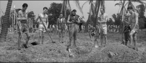 Chaplain Paul Anjou (Michael Goodliffe) delivers messages between camps in Latin during funerals in Val Guest's The Camp on Blood Island (1958)