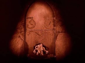 An imp breaks through a door in stop motion in Benjamin Christensen's Haxan (1922)