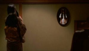 Shizuko (Masako) brushes her hair with Sadako (Rie Ino'o) reflected in the mirror in Hideo Nakata's Ring 2 (1999)