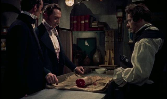 The Baron (Peter Cushing) examines some newly acquired parts in Terence Fisher's The Revenge of Frankenstein (1958)