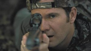 ... and suburban dad Chris Cleek (Sean Bridgers) spots her through his hunting rifle sight in Lucky McKee's The Woman (2011)