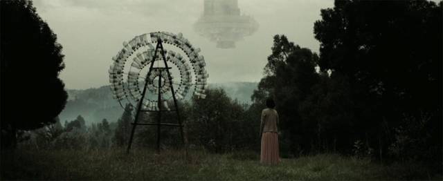 Birdy (Selam Tesfayie) stands beside one of her sculptures looking at the spaceship in Miguel Llanso's Crumbs (2015)