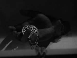 The Gamin (Adrienne Barrett)'s medallion gripped in the Fat Man (Bruno Ve Sota)'s severed hand in John Parker's Dementia (1953)