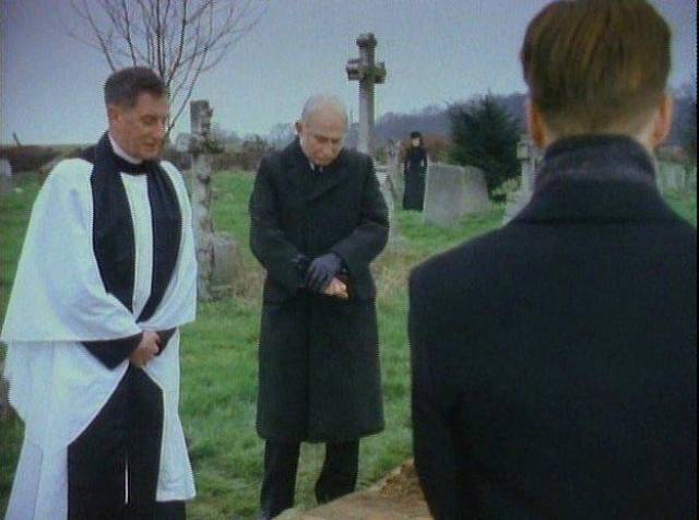 At Mrs. Drablow's funeral, Arthur Kidd (Adrian Rawlins) sees a silent figure watching in Herbert Wise's The Woman in Black (1989)