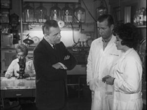 A government agent seeks answers from baffled scientists in Bill Rebane and Herschell Gordon Lewis’s Monster a Go-Go (1965)
