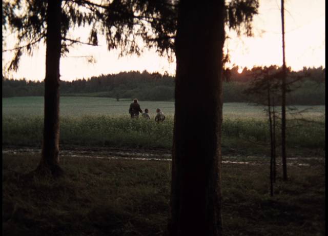 The camera retreats into darkness as the old mother and young Alexei and his sister walk into the distance in Andrei Tarkovsky's Mirror (1975)