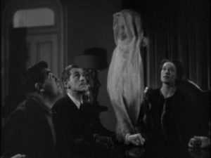 Dr. Blair (Boris Karloff) attends a phony seance conducted by medium Mrs. Walters (Anne Revere) in Edward Dmytryk's The Devil Commands (1941)