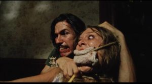The Hitchhiker (Edwin Neal) offers Sally (Marilyn Burns) to Grandpa (John Dugan) in Tobe Hooper's The Texas Chain Saw Massacre (1974)