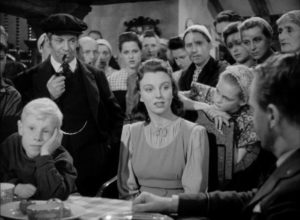 Schoolteacher Els Maartens (Pamela Brown) presides over a village meeting in Michael Powell's One of Our Aircraft Is Missing (1942)