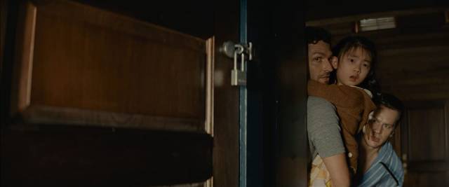 Andrew (Ben Aldridge), Eric (Jonathan Groff) and Wen (Kristen Cui) hear strangers breaking in in M. Night Shyamalan's Knock at the Cabin (2023)