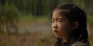 Wen (Kristen Cui) sees strangers approaching through the woods in M. Night Shyamalan's Knock at the Cabin (2023)