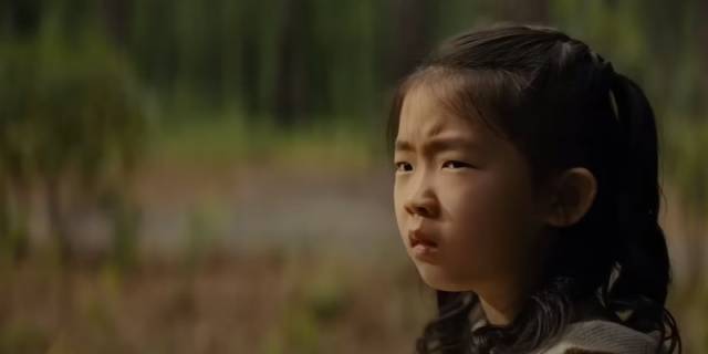 Wen (Kristen Cui) sees strangers approaching through the woods in M. Night Shyamalan's Knock at the Cabin (2023)