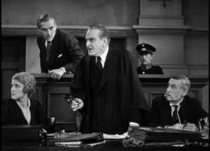 Paul Held (Frank Morgan)'s summation at the trial climaxes with him aiming a revolver at his wife in James Whale's The Kiss Before the Mirror (1933)