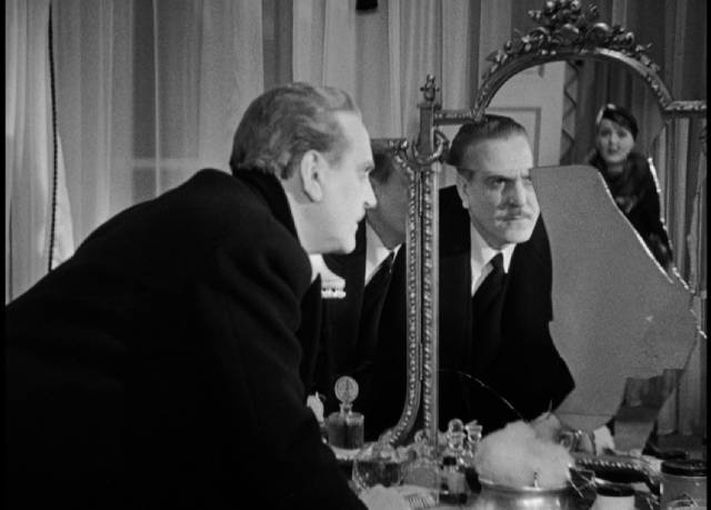 Smashing his wife (Nancy Carroll)'s vanity mirror may heal Paul (Frank Morgan)'s jealousy in James Whale's The Kiss Before the Mirror (1933)