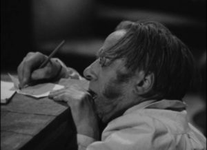 Professor le Blanc (Wallace Evennett) tries to scribble his murderer's name before he dies in George King's The Face at the Window (1939)
