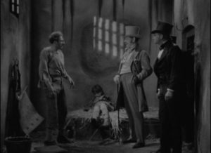 Prisoner George Fielding (Ian Colin) stands up to Squire Meadows (Tod Slaughter) over brutality inflicted on inmates in David MacDonald's It's Never Too Late to Mend (1937)