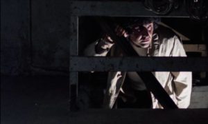The stage director (Marzio Honorato) searches for something behind the screen in Giuliano Montaldo's Closed Circuit (1978)