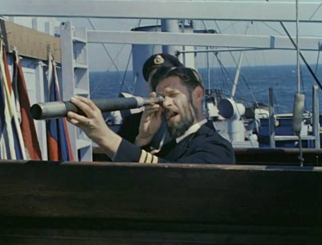 The crew of a freighter spot the lifeboat unaware of the lurking submarine in Pat Jackson's Western Approaches (1944)