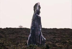 The standing stone watches over The Volunteer (Mary Woodvine)'s daily routines in Mark Jenkin's Enys Men (2022)