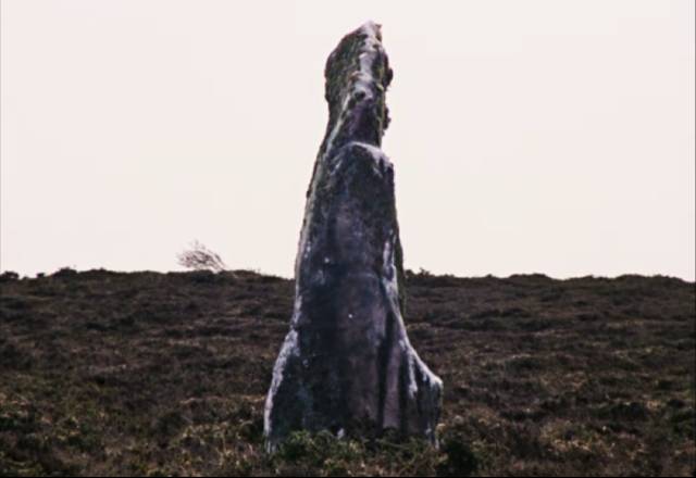 The standing stone watches over The Volunteer (Mary Woodvine)'s daily routines in Mark Jenkin's Enys Men (2022)